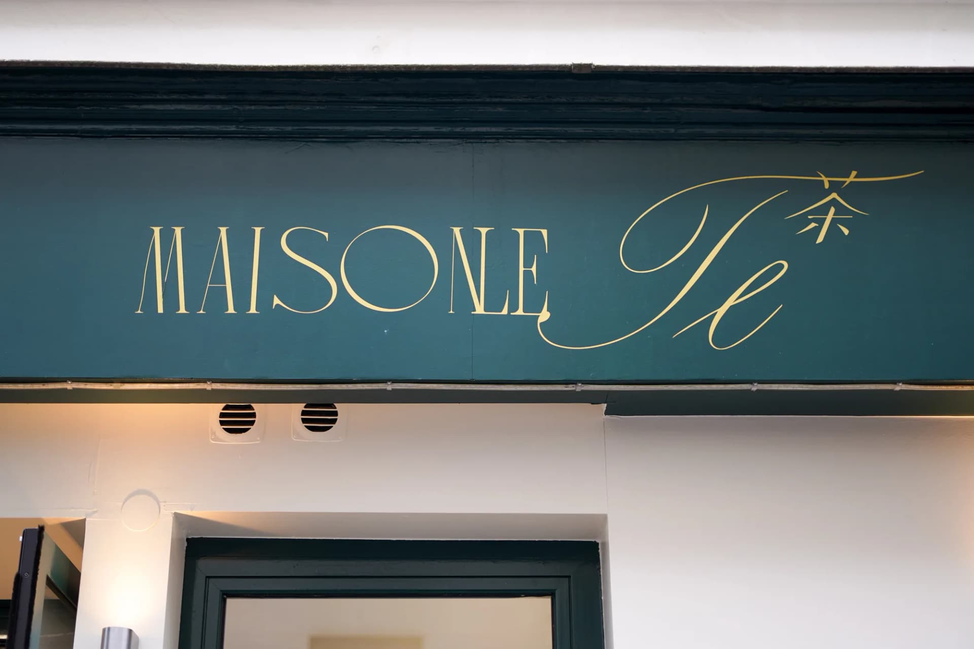 Enseigne dorée MAISON LE TÊ en lettres calligraphiées sur fond vert
