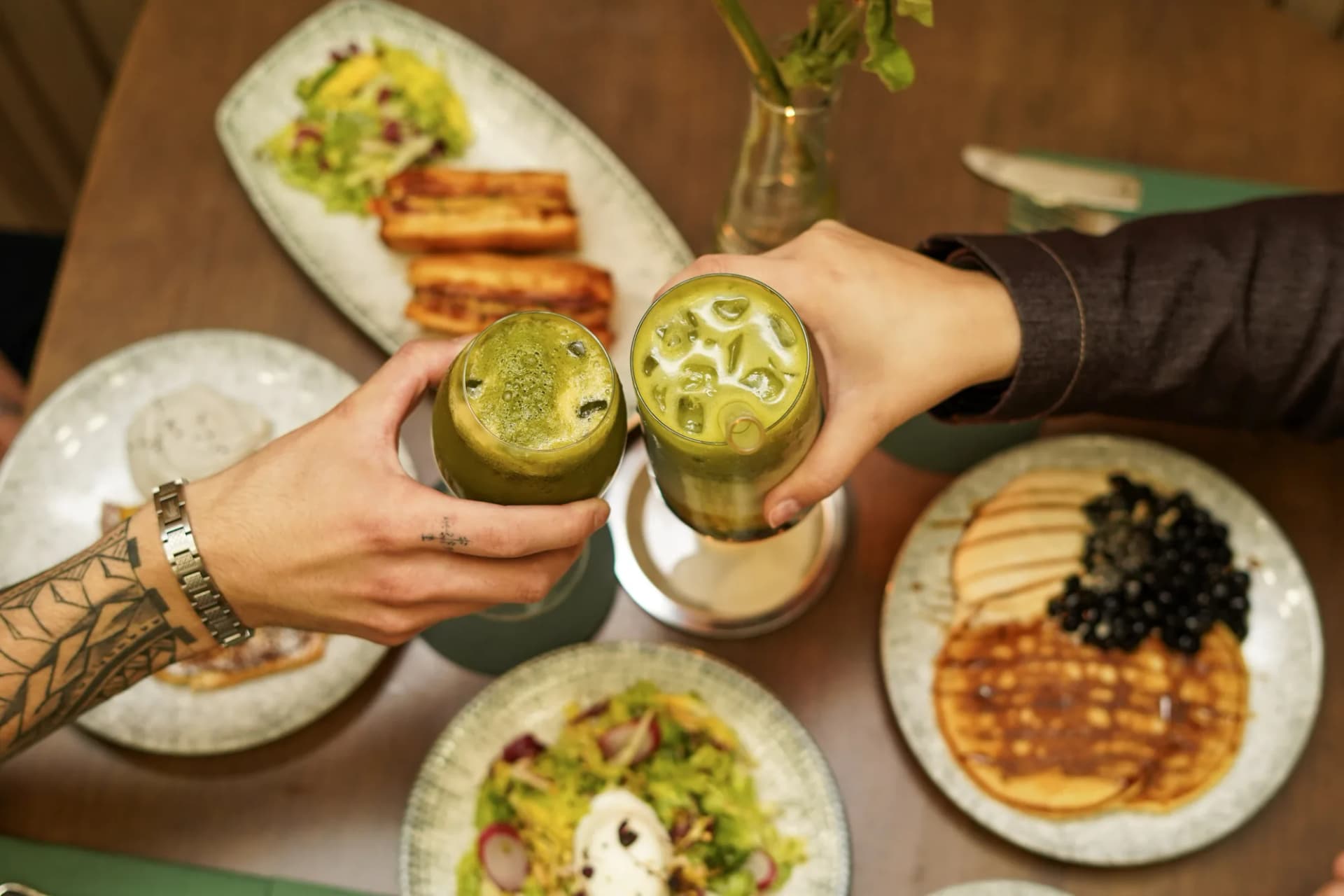 Trinquer avec deux matcha lattes top-down — ambiance partage Le Tê & MAISON LE TÊ