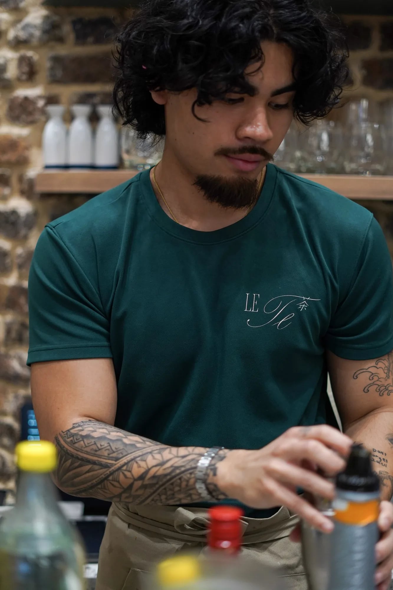 barista cheveux boucles bras tatoue prepare boisson Le Te