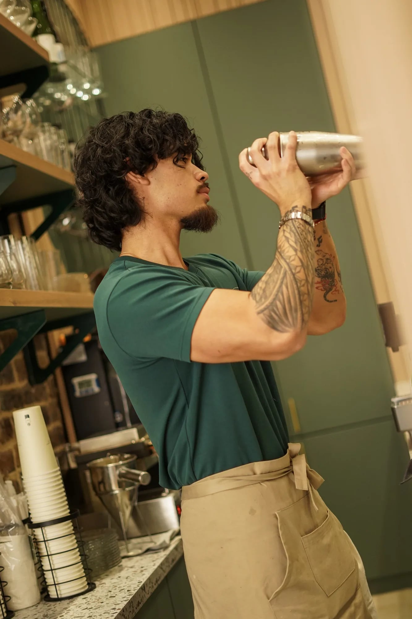 Barman Le Te shake cocktail, etageres verres derriere