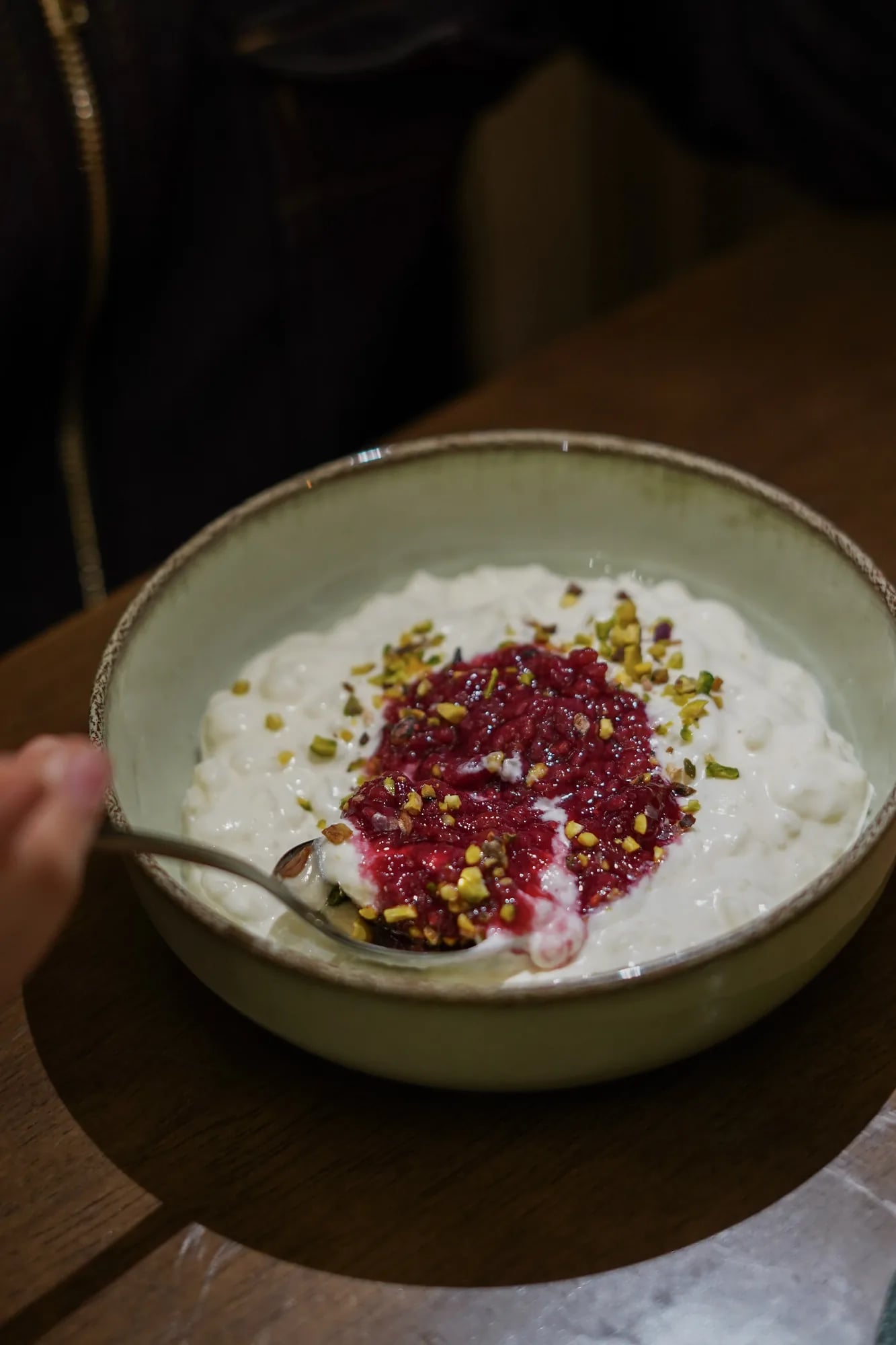 Riz au lait framboise, main flou avec cuillere, lumiere chaude