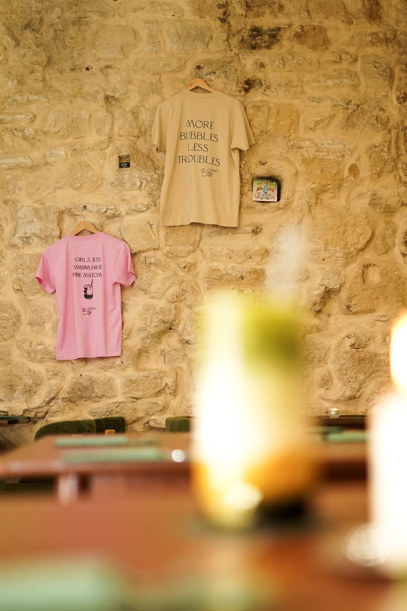 deux tshirts merch suspendus mur pierre rose beige