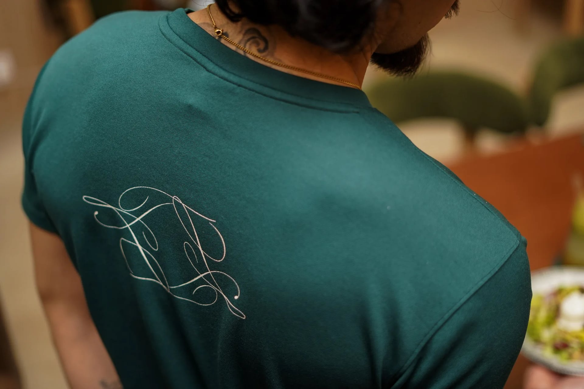 Detail logo Le Te calligraphie blanc sur t-shirt vert serveur